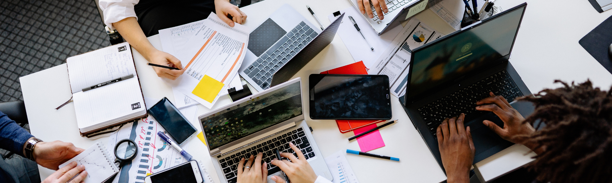 Coworkers collaborating on media planning and buying project aerial view of desk